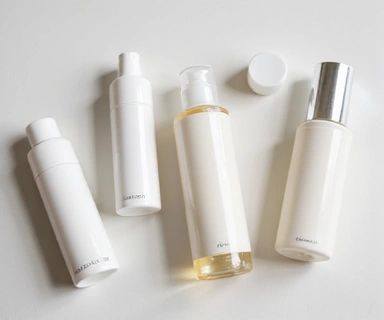 Close-up of various facial care products like cleansers, toners, and serums on a minimalist white background.